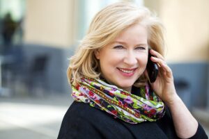 photo of mature blonde woman is calling on a cell phone, outdoors in spring
